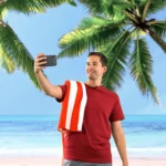 A man taking a selfie on a tropical beach.