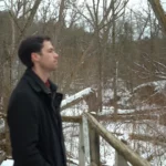 A man walking through snowy woods.
