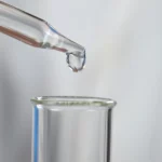 A dropper depositing a liquid into a flask.