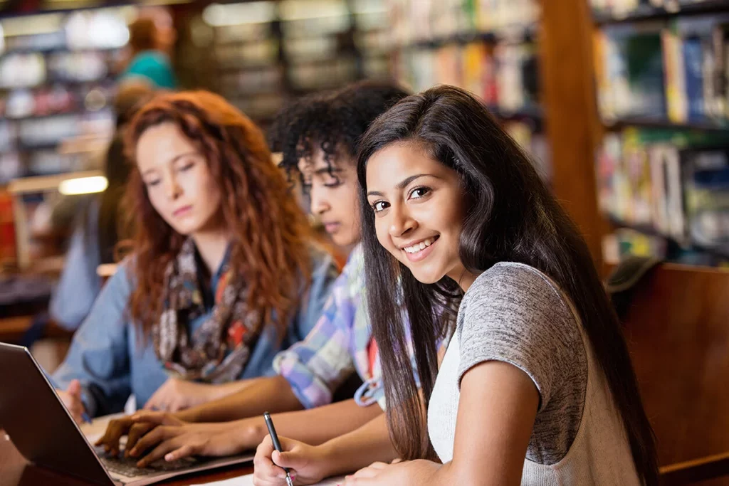 A group of students sitting at a table in a library.
