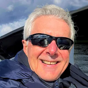A man wearing sunglasses and a jacket on a boat.