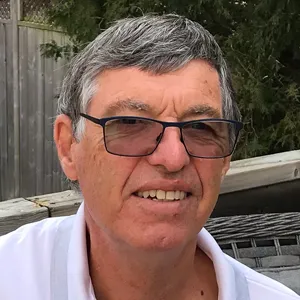 An older man wearing glasses and a white shirt.