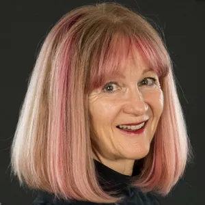 A woman with pink hair smiling for the camera.