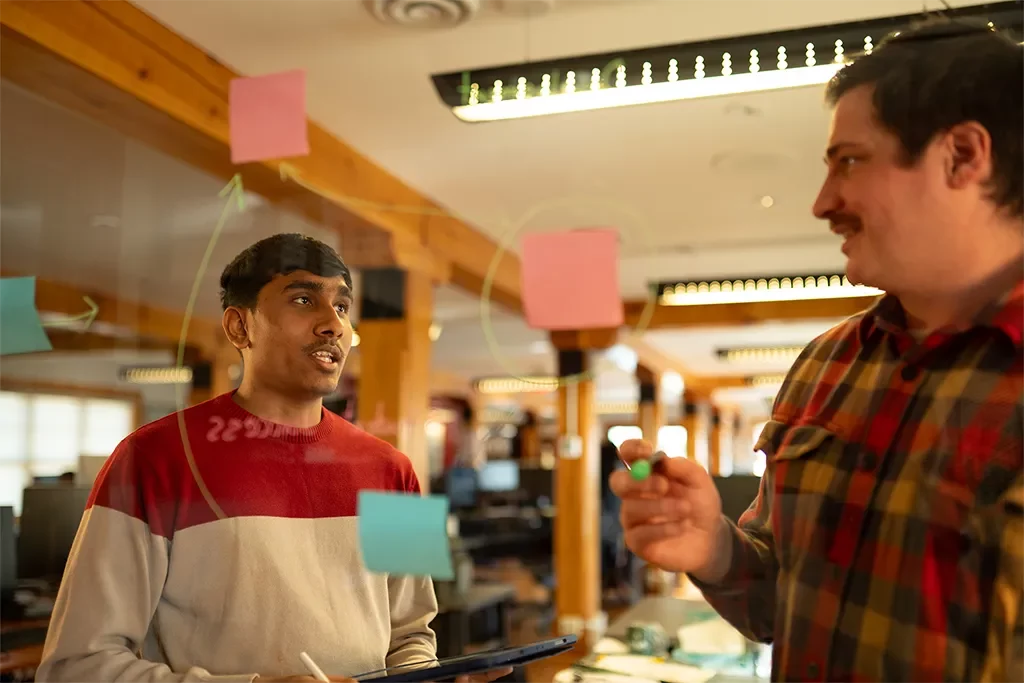 A group of people standing in front of a board with sticky notes.