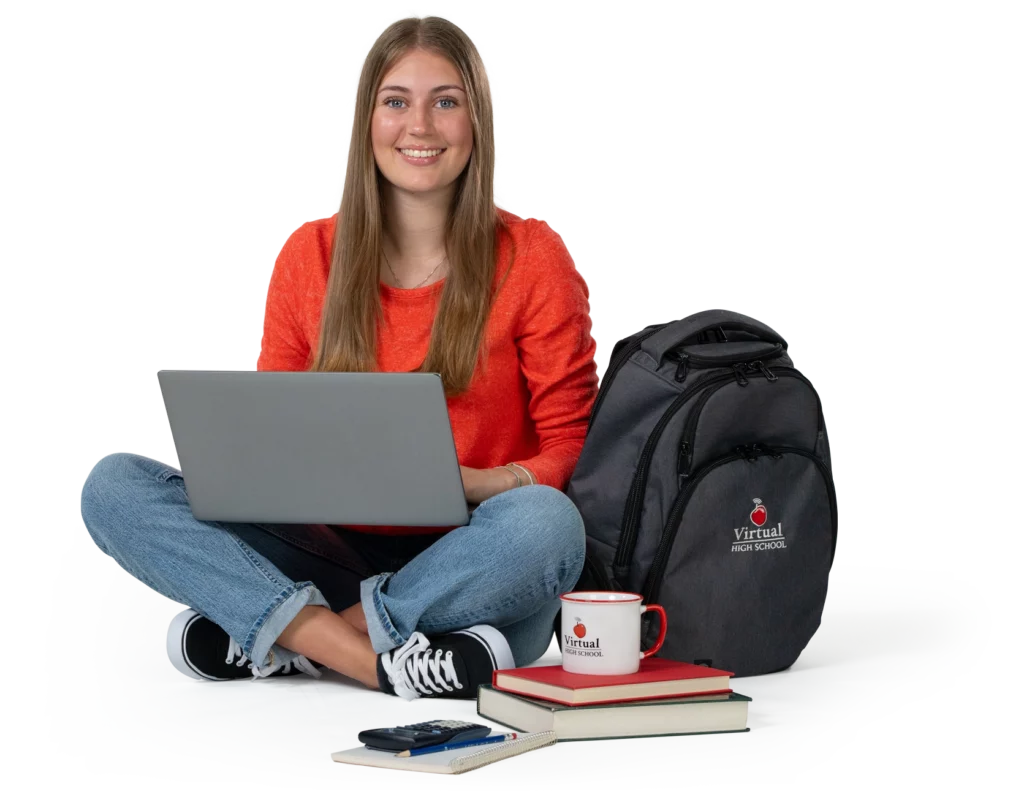 Smiling young lady sitting cross-legged with a laptop, books, and coffee cup.